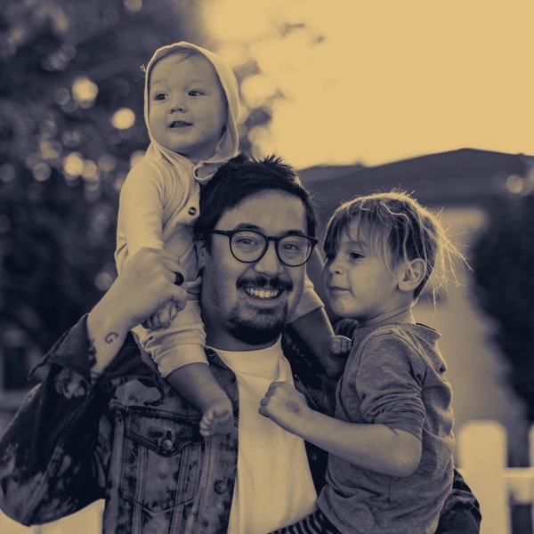 Padre joven sonriendo con dos hijos pequeños — perfil familiar